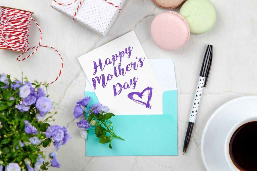 Happy Mothers Day Card Beside Pen, Macaroons, Flowers, and Box Near Coffee Cup With Saucer-min